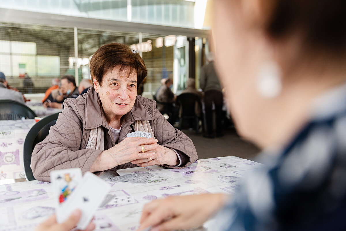 Seniorin ist am Karten spielen. Sie spielen zu zweit. 